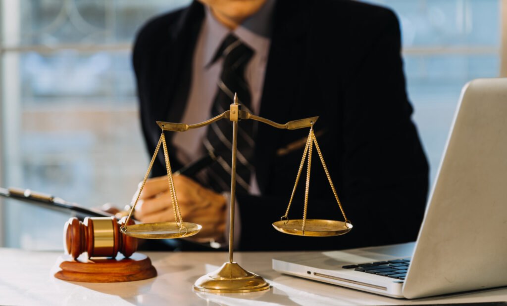 No Win No Fee whiplash lawyer at desk with scales, gavel and open laptop.