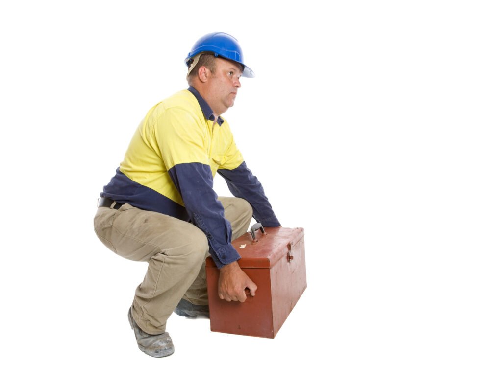 A worker kneeling down to lift up a box.