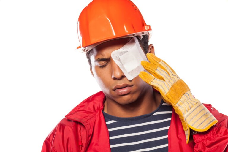 A worker in an orange helmet has a plaster over their injured eye.