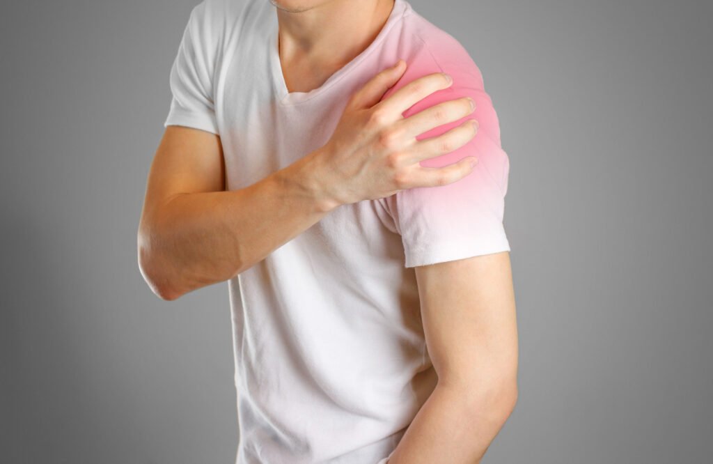 A person holding their shoulder which is highlighted in red to show significant pain. They could seek a shoulder injury compensation payout if it was caused by another party's negligent actions
