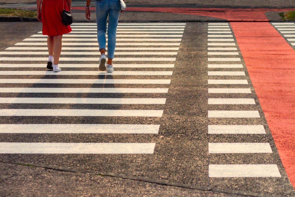 Two people walk across a zebra crossing.