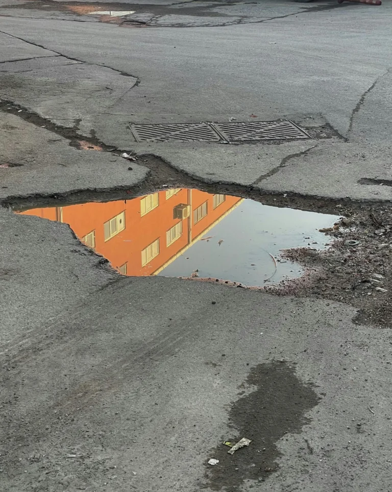 A photo of a dangerous pothole filled with water.