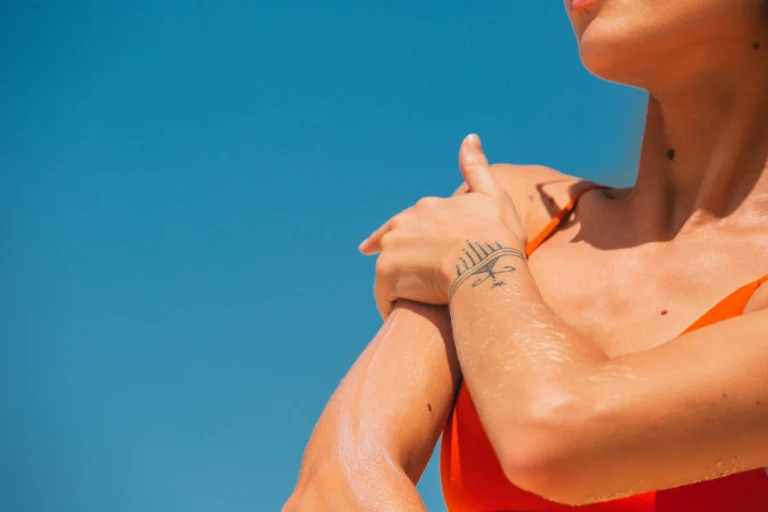 A picture of a woman applying sun cream to the top of her arm.