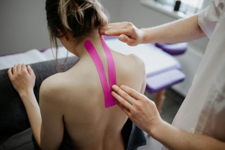 A woman with supporting tape on her back being examined by a doctor.