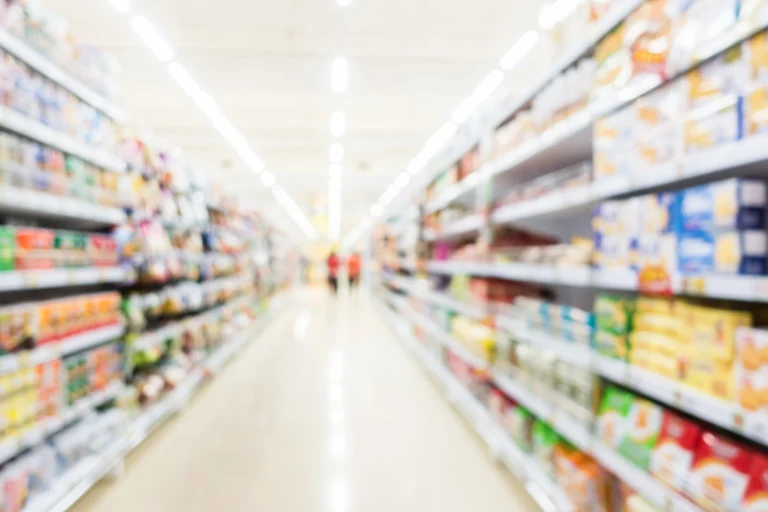 a view down a long supermarket aisle with two customers at the far end.